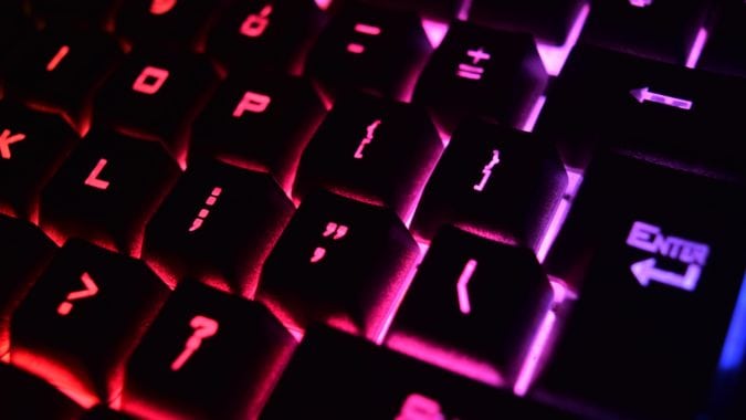 A closeup of a keyboard whose letters are illuminated in pink