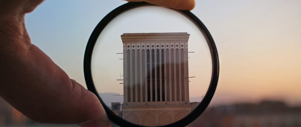 A building is focused through a lense being held in a person's hand