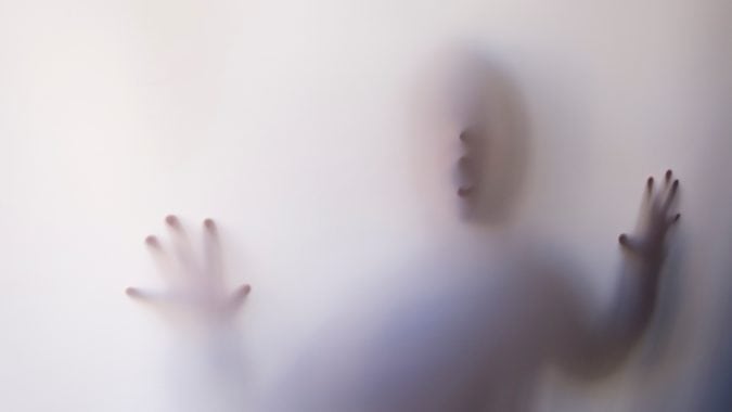 An individual is pressed against a curtain, making them very blury.
